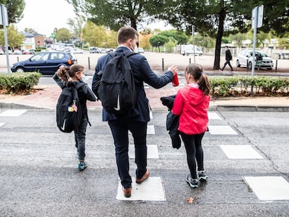 Un padre lleva a sus hijas al colegio.