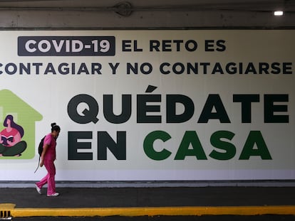 Una mujer camina frente a un letrero que pide quedarse en casa durante la contingencia de covid-19 en Ciudad de México.