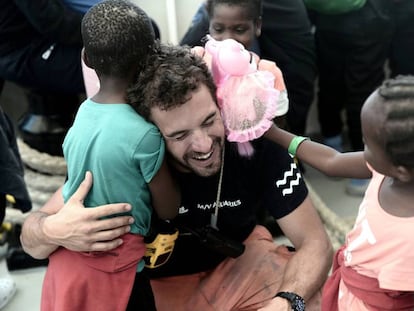 Un miembro de la tripulación del 'Aquarius' abraza a dos niños a la llegada al puerto de Valencia.