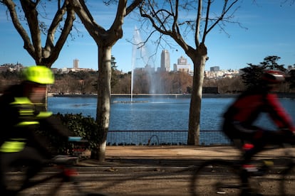 Dos ciclistas pasan por delante del lago de la Casa de Campo.