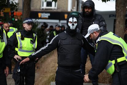 Un agente de policía registra a una persona enmascarada en Walthamstow, al noreste de Londres, el 7 de agosto. 