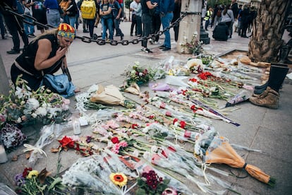 Una mujer frente a un altar con flores en recuerdo a los fallecidos en la plaza del Ayuntamiento de Valencia.