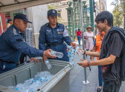 Cadetes de la policía de Monterrey reparten botellas con agua en el centro de la ciudad.