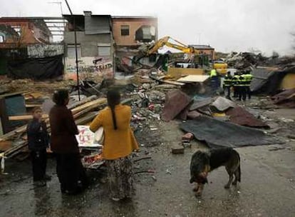 Vecinos del poblado de Pitis observan cómo una excavadora derriba una vivienda ante cuatro policías municipales.