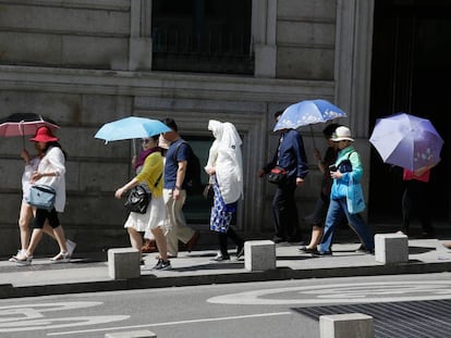 Tourists use umbrellas to keep the sun off in Madrid.