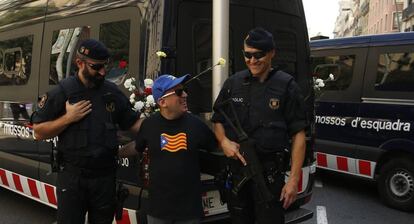 Un hombre con la camiseta con la estelada posa para una foto con dos mossos