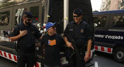 Un home amb una samarreta amb l'estelada es fa una foto amb dos mossos.