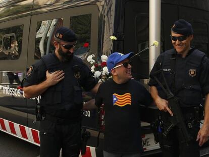 Un home amb una samarreta amb l'estelada es fa una foto amb dos mossos.
