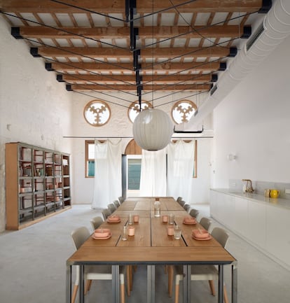 La cocina, lacada en blanco, con encimeras de mármol de Macael y abierta, es un diseño de Cristina Pons realizado por Carpintería Biniarroca. La gran mesa está formada por varias unidades del modelo Smart Tables, ideados por Archimboldi. La silla Belloch, diseñada por Lagranja, la produce Santa &Cole. La vajilla de bambú es de Ekobo. La lámpara de techo la produjo, a mano, la empresa danesa Knit Wit.