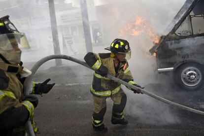 Los bomberos trabajan para extinguir un autobús en llamas, incendiado durante el tiroteo en el que ocho presuntos narcotraficantes fueron abatidos a tiros por la Marina mexicana en Tláhuac, Ciudad de México