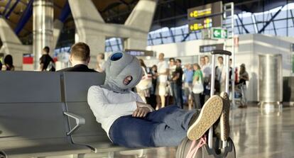 Un viajero descansa en un aeropuerto con el Ostrich Pillow, creada en un estudio creativo en el madrileño barrio de Tetuán.