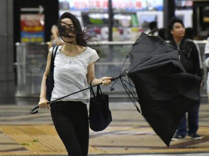 Una mujer sujeta un paraguas roto por las fuertes rachas de viento que ha causado el tifñon Jebi en Osaka (Japón). 