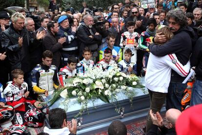 El padre de Simoncelli abraza a su hija ante el féretro del piloto, a la salida del funeral.