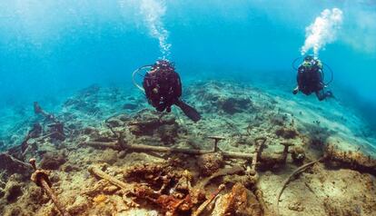 Dos submarinistas sobre los restos del timón del destructor 'Plutón', en la bahía de Santiago de Cuba.