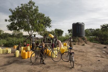 Varios niños sursudaneses cogen agua en un punto de distribución dentro del campo de refugiados.