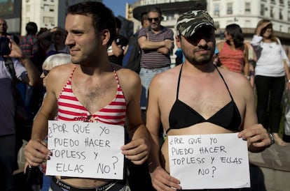 Dois homens que se uniram ao protesto com os cartazes: "Por que eu posso fazer topless e elas não?"