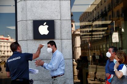 Un hombre toma la temperatura en la entrada de una tienda de Apple en Madrid, el 30 de junio.