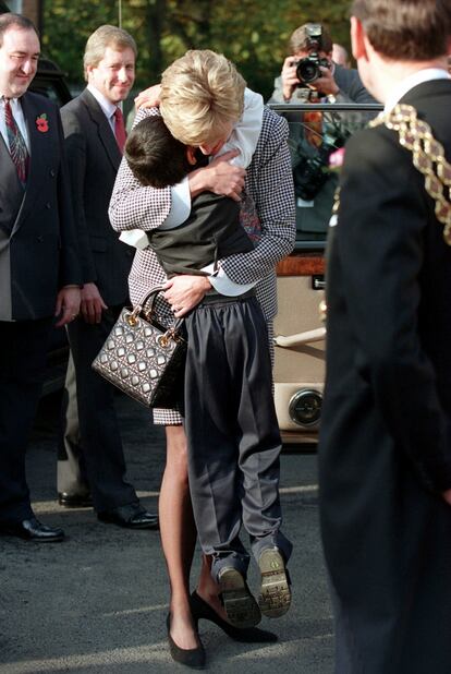 Lady Di abraza a un niño durante la inauguración de la Fundación de Birmingham con su bolso hecho en especial para ella.