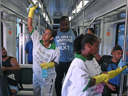 Dos trabajadoras desinfectan las barras de sujeción de un vagón de tren en Río de Janeiro.
