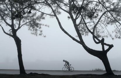 Ciclista pedala sob a névoa por Del Mar, cidade do condado de San Diego, Califórnia (EUA).