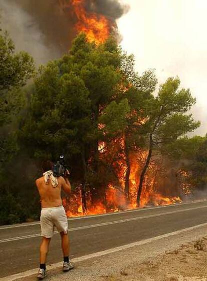 Un camarógrafo toma imágenes del fuego  cerca de Zaharo.