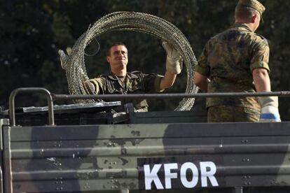 Soldados alemanes de la KFOR descargan alambrado en el principal puente que divide la ciudad de Mitrovica, Kosovo.