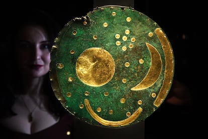 An employee at the British Museum poses next to the Nebra sky disc at the new Stonehenge exhibition.