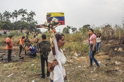 Una mujer sostiene un Cristo abajo del puente Simón Bolívar, cerca del Río Táchira.