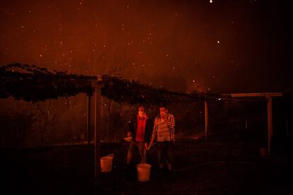 El incendio forestal se ha dirigido hacia Macao, un municipio cercano a la ciudad de Santarem, donde se espera que las temperaturas alcancen 34 grados este domingo. En la imagen, vecinos de Amendoa ayudan en las labores de extinción.