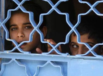 Dos niños observan una patrulla de soldados estadounidenses en Bagdad desde la puerta de su casa.