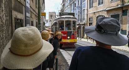Tourists wait for the arrival of the line 46 tram on Augusto Rosa Street, in the historic center of Lisbon.