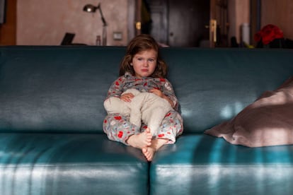 Una niña llora en el sillón de su casa. 