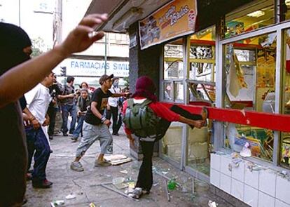 Unos manifestantes destrozan una tienda en el 35º aniversario de la matanza de Tlatelolco, el jueves.