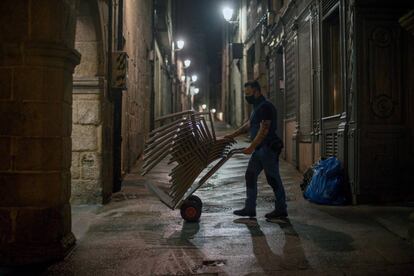 Un hombre recoge las sillas de una terraza en la Plaza Mayor de Ourense, este domingo cuando ha entrado en vigor el estado de alarma.