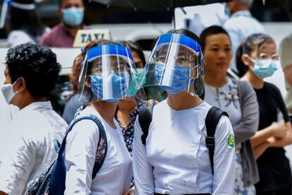 Dos alumnas se preparan para asistir a clase durante el primer día de reapertura de las escuelas secundarias públicas, tras el cierre provocado por al coronavirus, en Rangún (Birmania).