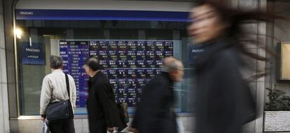 Peatones frente a un monitor de cotizaciones en Tokio. 