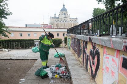 Una limpiadora recoge la basura acumulada en el parque de las Vistillas después del botellón del pasado 20 de junio.