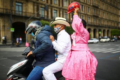 Tres personas protegidas con mascarillas viajan en una moto, en Ciudad de México.