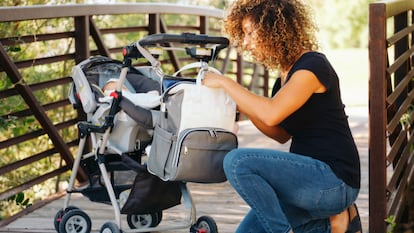 Una madre con su hijo buscando algún objeto en la bolsa del carrito.