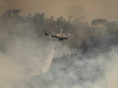 En la imagen, un helicóptero lanza agua al incendio.