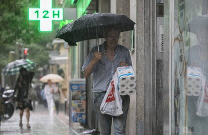 Un madrileño se protege de la lluvia en la calle de Ferraz.
