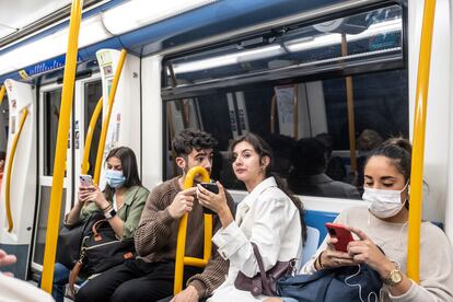 Una pareja conversa sin mascarilla en un vagón del metro de Madrid.