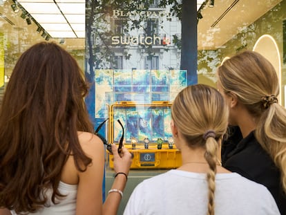 Tres clientas observan los relojes de Blancpain x Swatch expuestos en el escaparate de la boutique de Swatch de la calle Serrano.