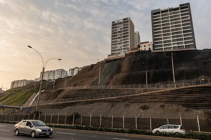 Autos recorren la pista bajo edificios construidos al borde del acantilado en el distrito de Magdalena del Mar.