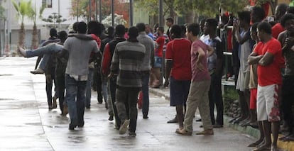 Un grupo de subsaharianos ayuda a los inmigrantes que han saltado este domingo en Melilla.