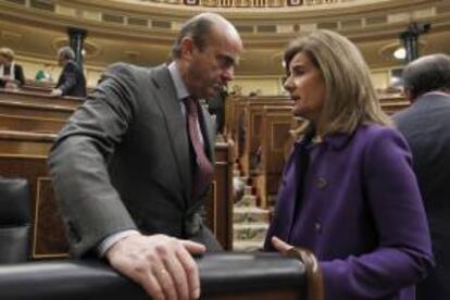 El ministro de Economía, Luis de Guindos (i), conversa con la ministra de Empleo y Seguridad Social, Fátima Báñez (d), durante la sesión de control al Gobierno, en el Congreso de los Diputados. EFE/Archivo