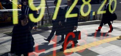 Una mujer reflejada en un monitor de cotizaciones en Tokio.