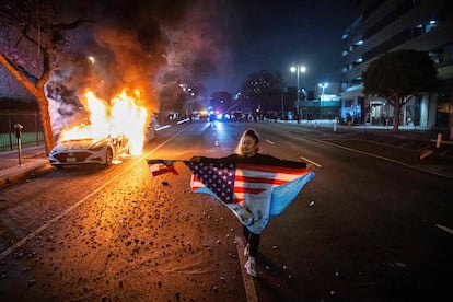 Una manifestante blande las banderas de México, Estados Unidos y de Guatemala durante las protestas en Los Ángeles en la madrugada del lunes al martes.
