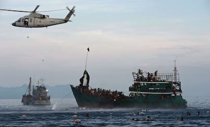 Imigrantes se atiram à água para pegar alimentos distribuídos por militares tailandeses.