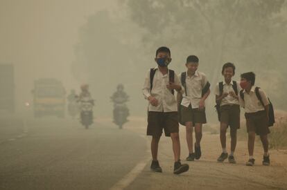 Niños de la ciudad indonesia de Jambi, en la isla de Sumatra, caminan bajo un ambiente contaminado por el humo proveniente de los incendios forestales que están activos en las islas del norte del país.